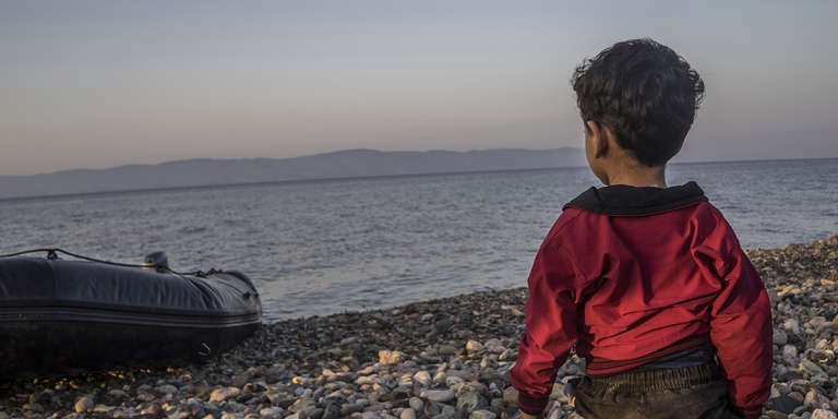 A young boy looks out to sea from the shores of the Greek islan